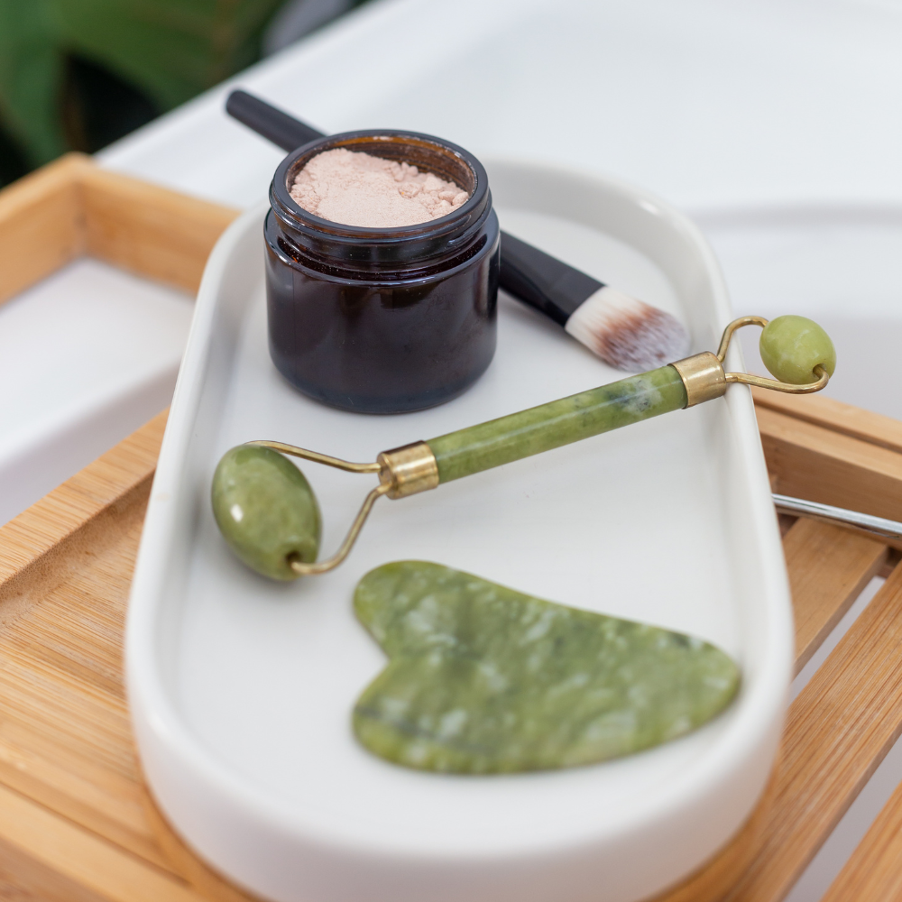 jade roller and gua sitting on a marble plate ready for a spa facial treatment.